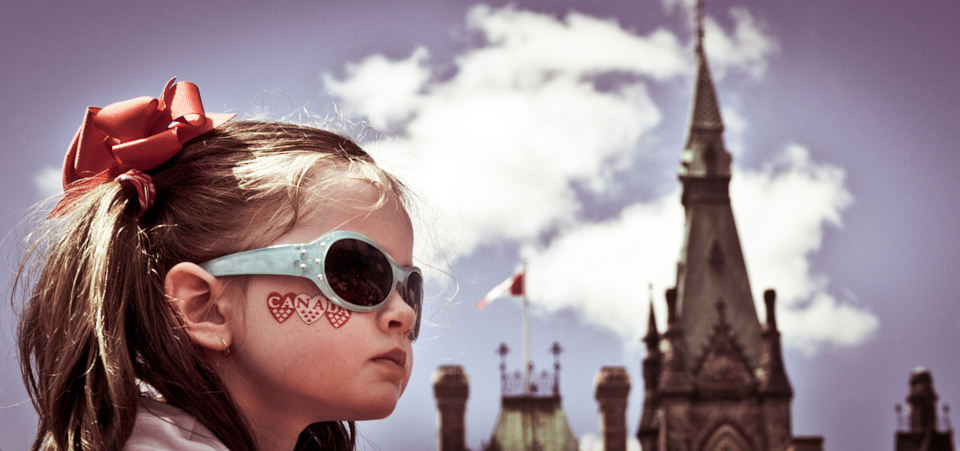 girl with bow tie and canada day face sticker in front of ottawa's parliament hill